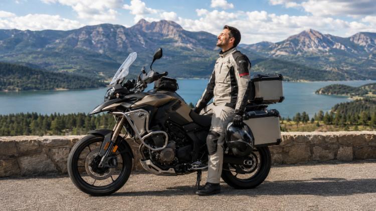 Biker đứng thư giãn bên xe moto giữa khung cảnh núi hồ thoáng đãng