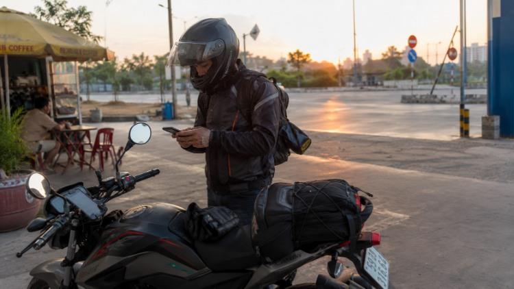 Biker chuẩn bị xe máy và kiểm tra điện thoại trước chuyến đến địa điểm đi phượt